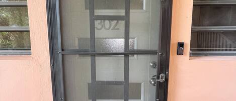 A door with a number "302" on it, a keypad lock, and a small window above the door.