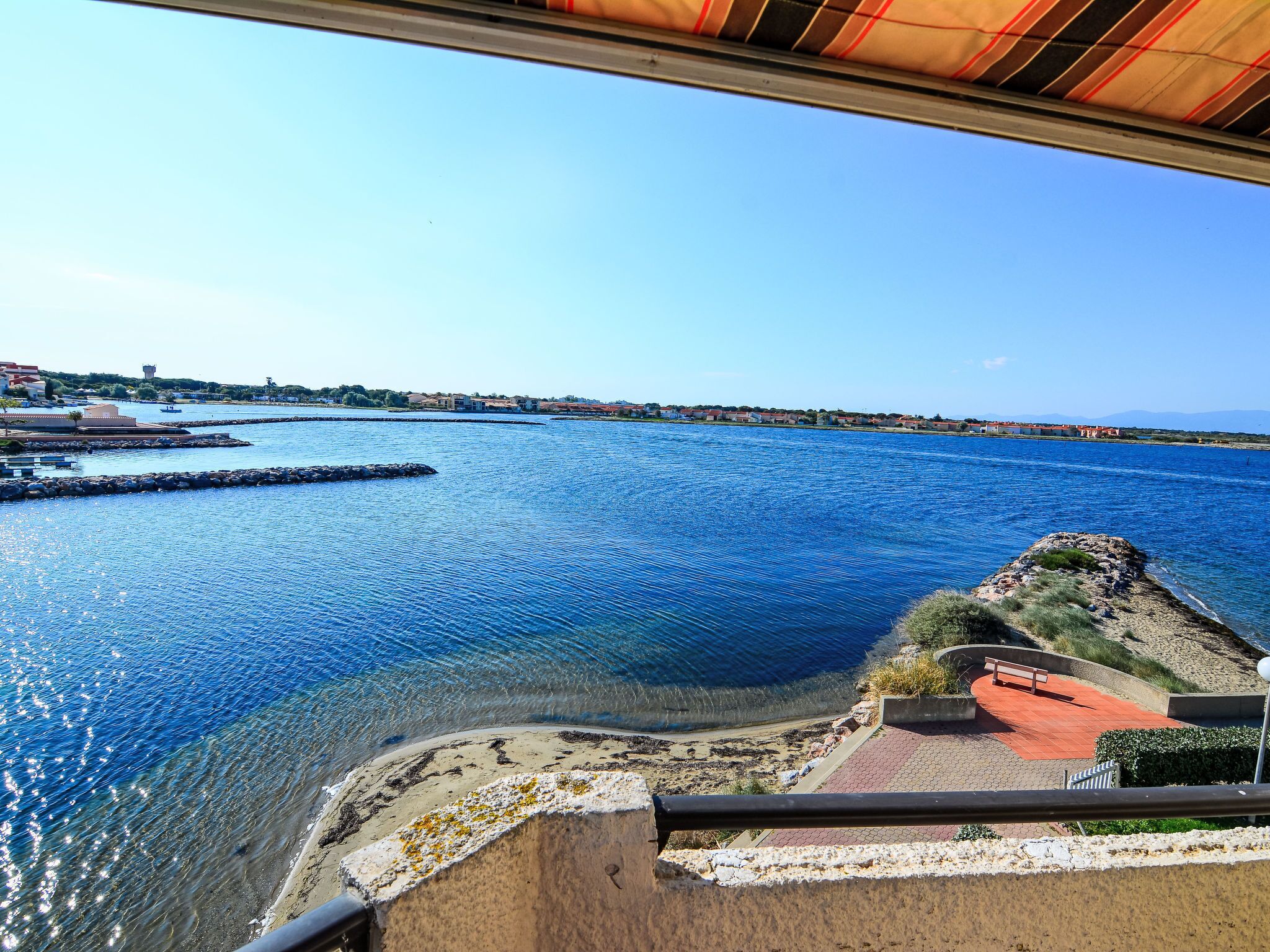 Blick auf die Küste mit blauem Meer, felsigem Ufer und einer in der Ferne liegenden Stadt.