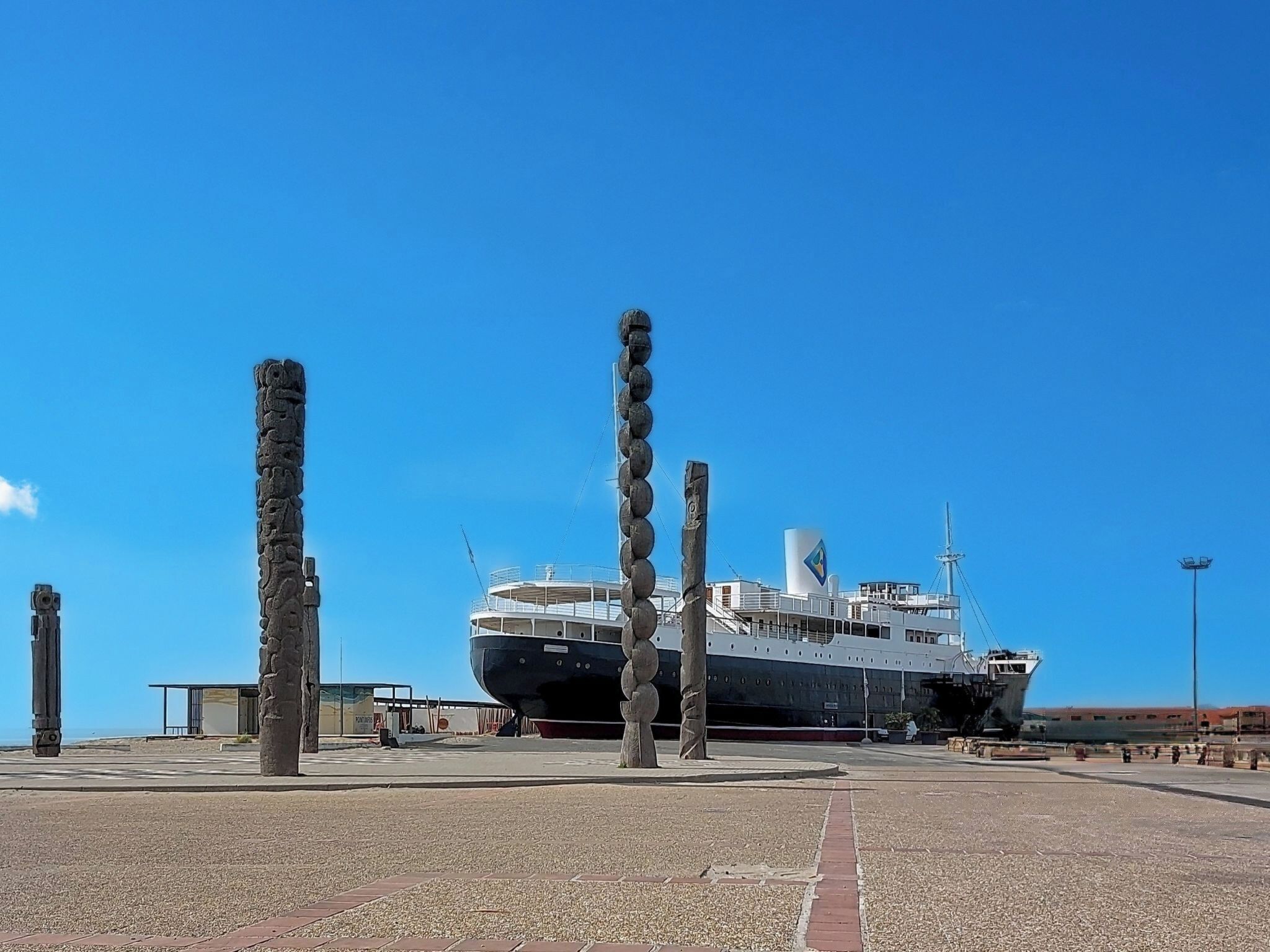 Un grand navire était amarré dans un port, sous un ciel d’un bleu éclatant.