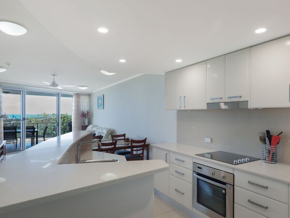 A modern kitchen with a central island, built-in oven, and a dining area with chairs.