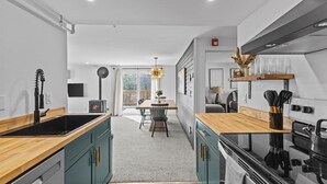 A modern kitchen with a central island, wooden countertops, and a built-in stove.