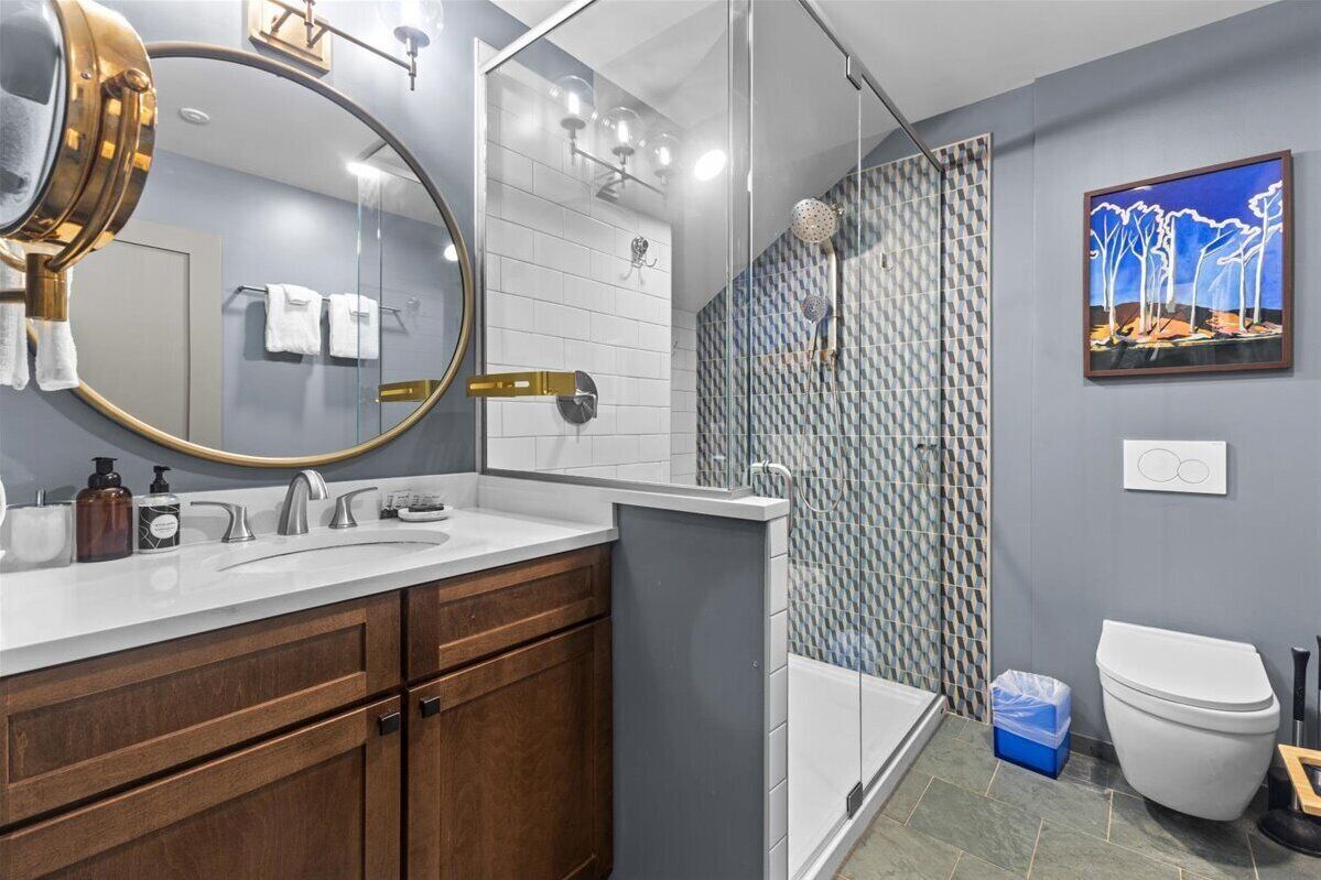 A modern bathroom with a large mirror, a shower, and a toilet.