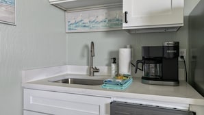 Een keuken met een spoelbak, een koffiezetapparaat en een vaatwasser.