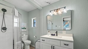 Een badkamer met douche, toilet, wastafel en opbergmeubel.