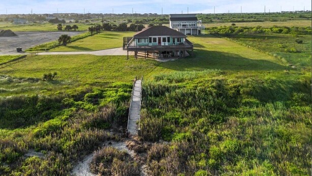 Een huis aan de kust met een houten terras en een pad ernaartoe.