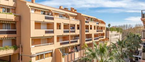 A multi-story hotel with balconies, a ground floor restaurant, and palm trees.