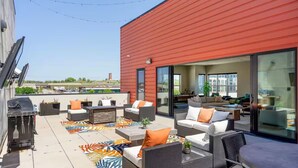 Une terrasse sur le toit, aménagée avec du mobilier d’extérieur, un barbecue et offrant une vue sur le panorama urbain.