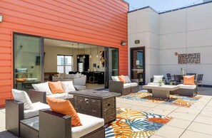 An outdoor patio area with wicker furniture, a patterned rug, and a glass door leading to an interior space.