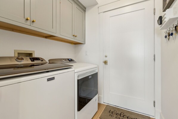 A compact laundry area with a washing machine and dryer, a microwave, and a cabinet with a small shelf above.
