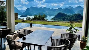 Un espacio al aire libre con mesa y sillas, con vistas a un paisaje montañoso y una masa de agua.