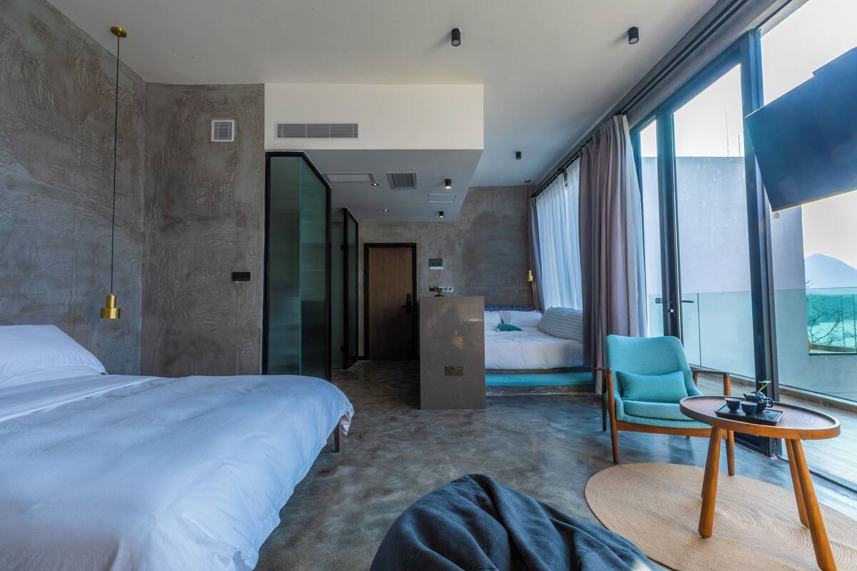 Ett modernt hotellrum med en stor säng, en sittgrupp med ett bord och utsikt över omgivningarna.