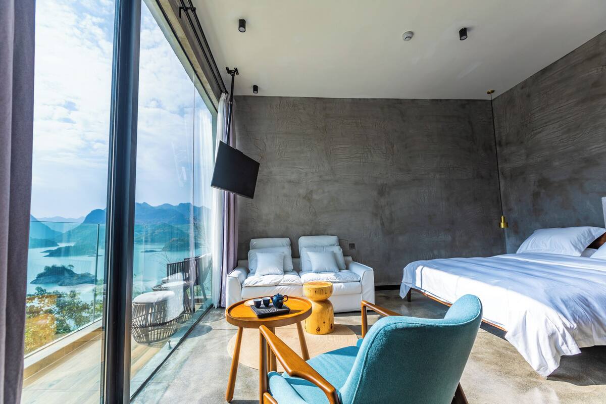 Ett modernt hotellrum med en stor balkong, en säng, en soffa och ett litet bord.