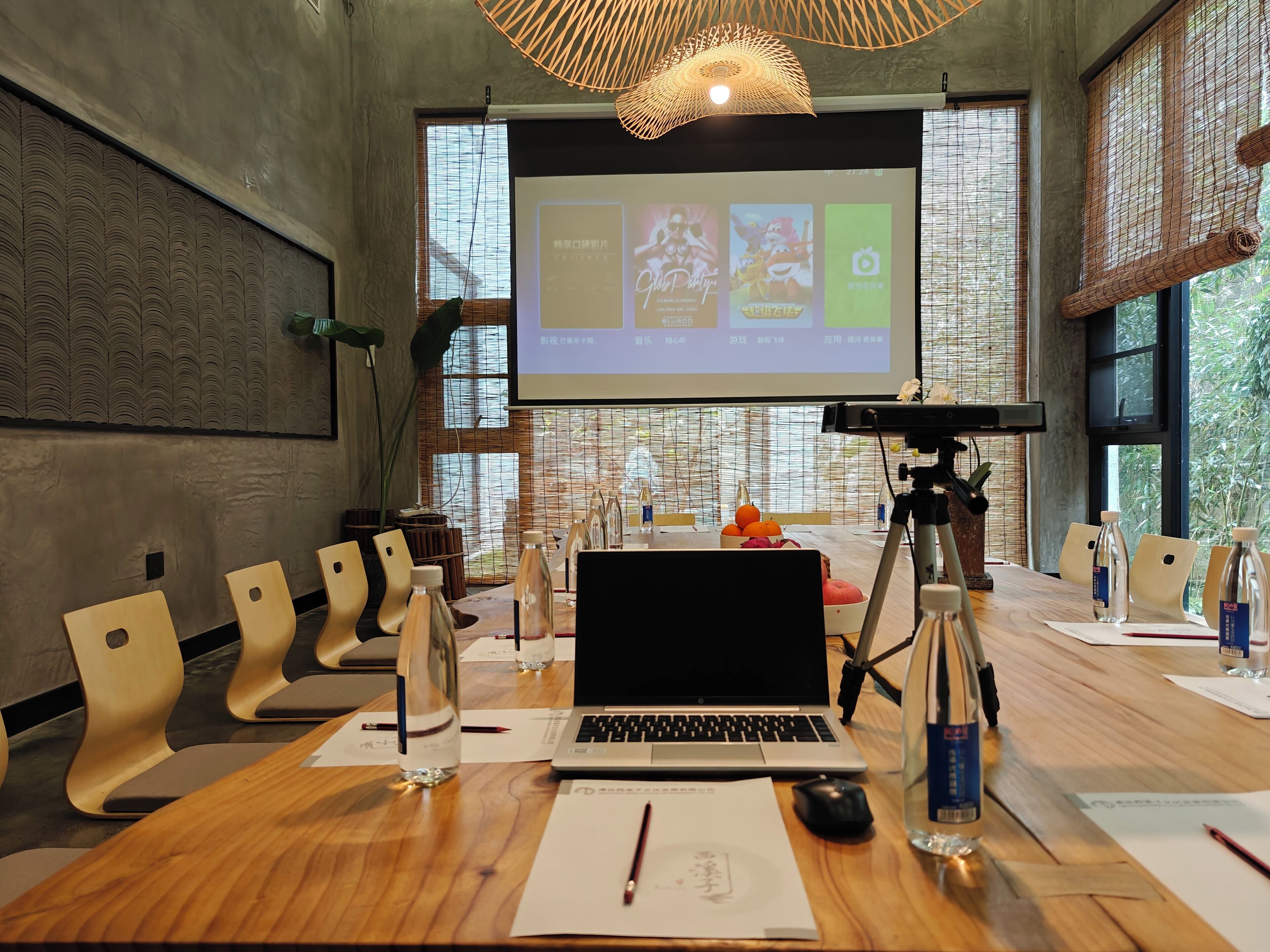 Un salón de conferencias con una laptop, una pantalla de proyector y una mesa de madera.