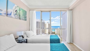 A hotel room with a large window, a bed, a nightstand, and a painting of a surfer. - Chevron Renaissance Ocean View (Surfers Paradise)