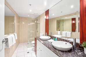 A modern bathroom with two sinks, a glass shower enclosure, and a large mirror. - Chevron Renaissance Ocean View (Surfers Paradise)
