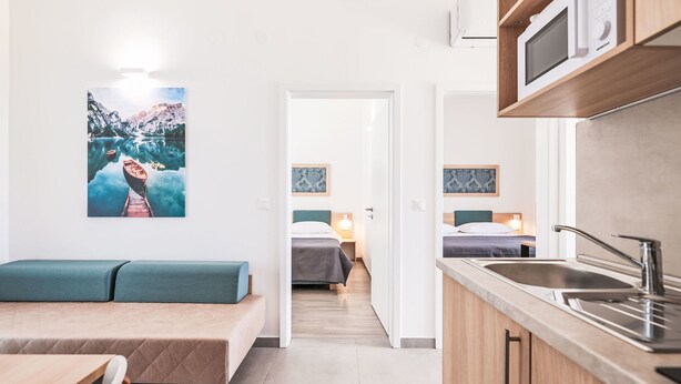 Habitación de hotel moderna con kitchenette, comedor y zona de dormitorio.