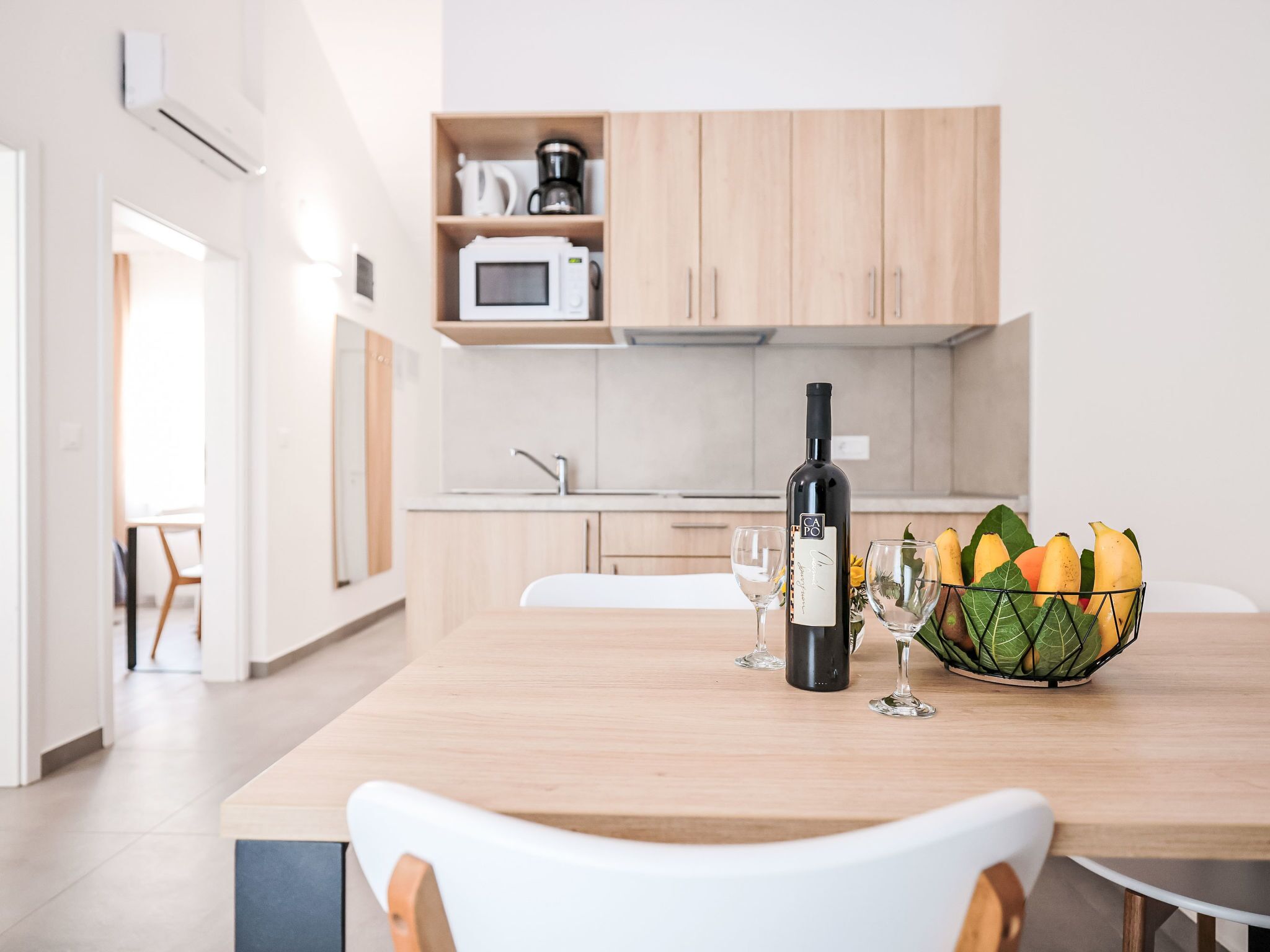 Une cuisine moderne avec des meubles en bois, un four à micro-ondes et une bouteille de vin posée sur le plan de travail.