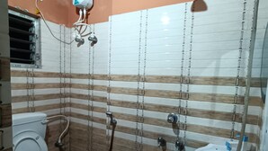 Un bagno con pareti rivestite di piastrelle a righe, un water, un lavandino e una doccia.