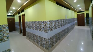 Un corridoio con pareti decorate da motivi, pavimento piastrellato e illuminazione incassata.