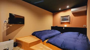 Une chambre à coucher avec un lit, un téléviseur fixé au mur et une fenêtre avec des stores.