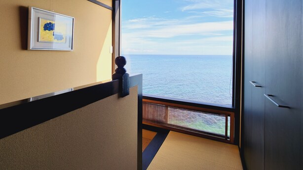 A room with a large window offering a view of the sea. - Shionomi (Himi)