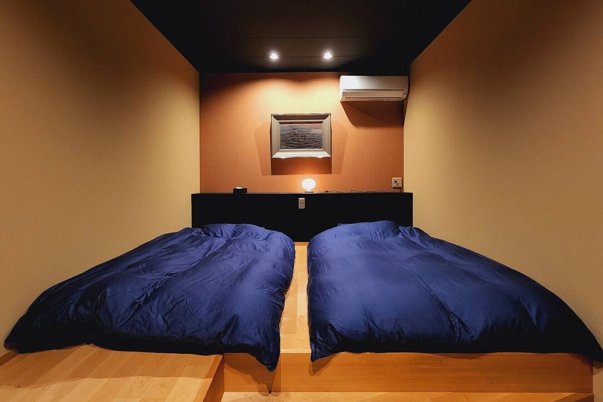 Une chambre avec un lit, un climatiseur fixé au mur et un tableau encadré.