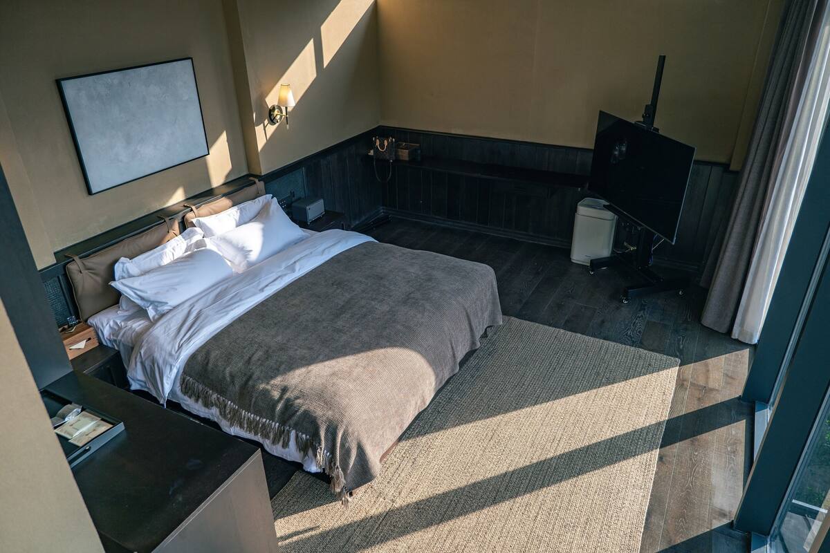 A neatly arranged bedroom with a bed, bedside tables, a desk, and a television.