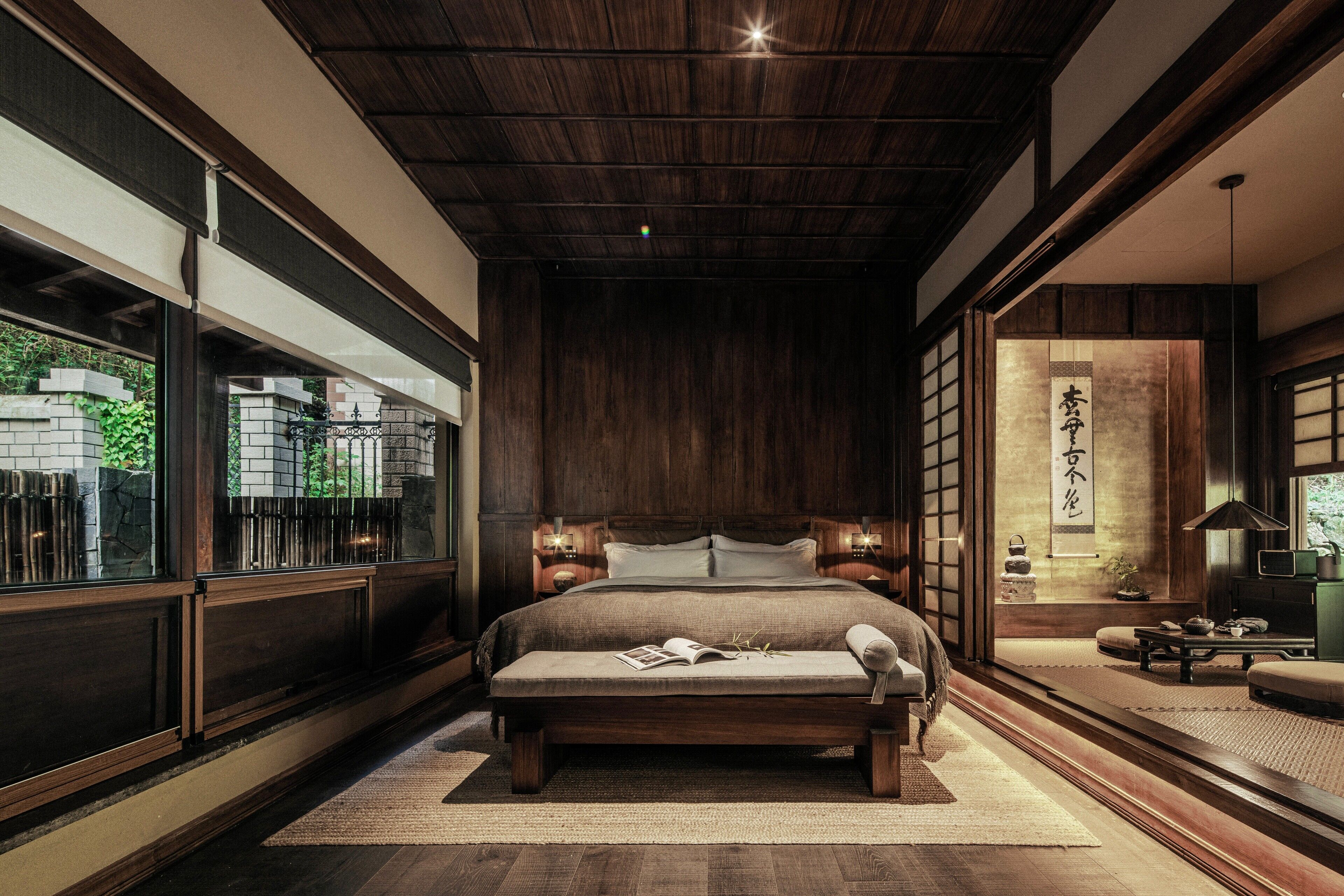 Un dormitorio japonés tradicional con una cama grande, puertas correderas y vistas a un jardín.