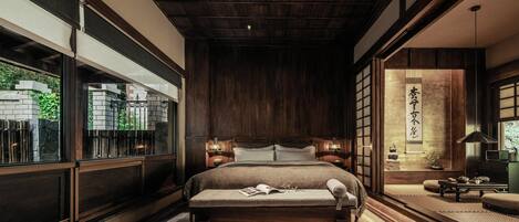 Un dormitorio japonés tradicional con una cama grande, puertas correderas y vistas a un jardín.