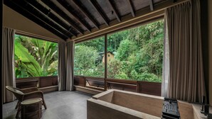 A room with a large bathtub, wicker chairs, and a view of lush greenery outside. - Jingdezhen Xingshan Shiwai Dongliyuan (Jingdezhen)