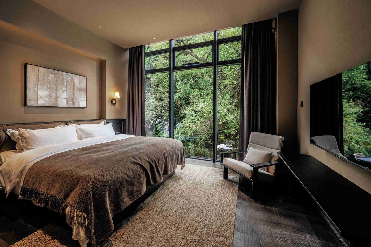 A modern bedroom with a large bed, a seating area, and a TV.