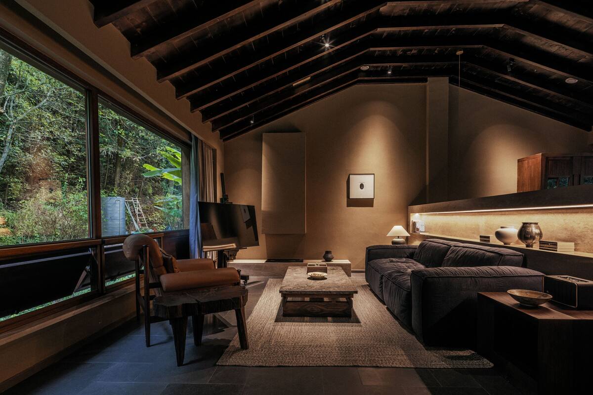 A modern living room with a large window, a sofa, a coffee table, and a TV.