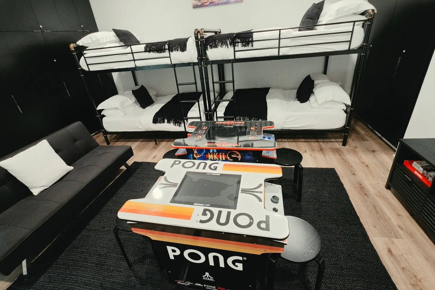 Quarto com beliche e uma mesa de jogos no centro.