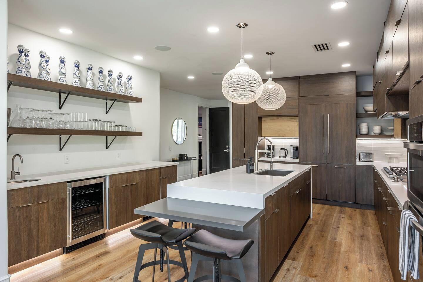A modern kitchen with a central island, wooden cabinets, and pendant lighting.