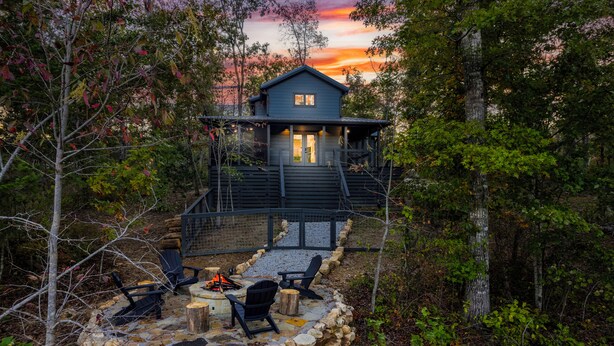 A cabin with a stone fire pit and outdoor seating, surrounded by trees and a stone wall. - Silent Princess, Tiny Home (Tracy City)
