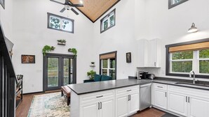 A modern kitchen with white cabinetry, a large island, and a view of the outdoors. - Silent Princess, Tiny Home (Tracy City)