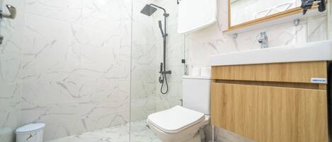 A modern bathroom with a shower, toilet, and vanity.