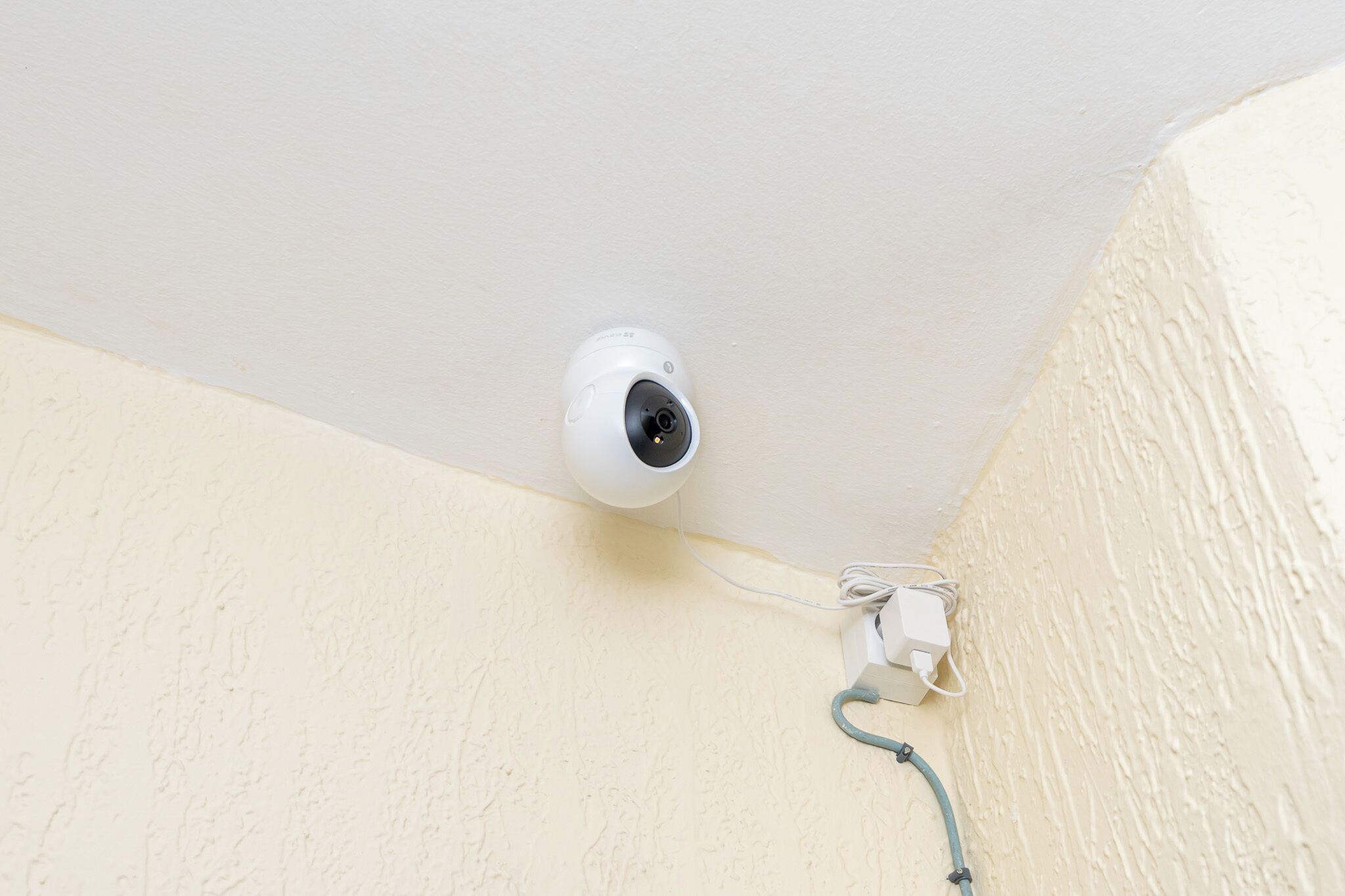 Une caméra de surveillance fixée à un mur, avec une prise de courant et un câble.