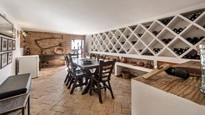 A dining area with a brick wall, a white wine rack, and a wooden table with chairs. - Rustic Retreat with Pool and Stunning Views (Altura)