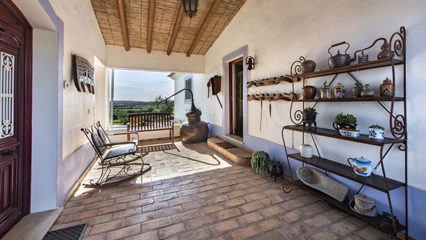 A cozy patio with a rocking chair, a large pot, and shelves with kitchenware. - Rustic Retreat with Pool and Stunning Views (Altura)