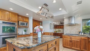 Una cocina con armarios de madera, electrodomésticos de acero inoxidable, encimeras de granito y una isla central.