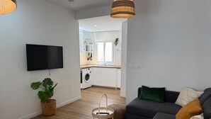 Un salon moderne avec un canapé, un téléviseur et un coin repas.