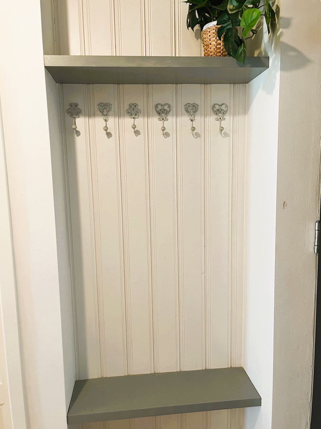 A white wall with vertical paneling and a grey shelf.