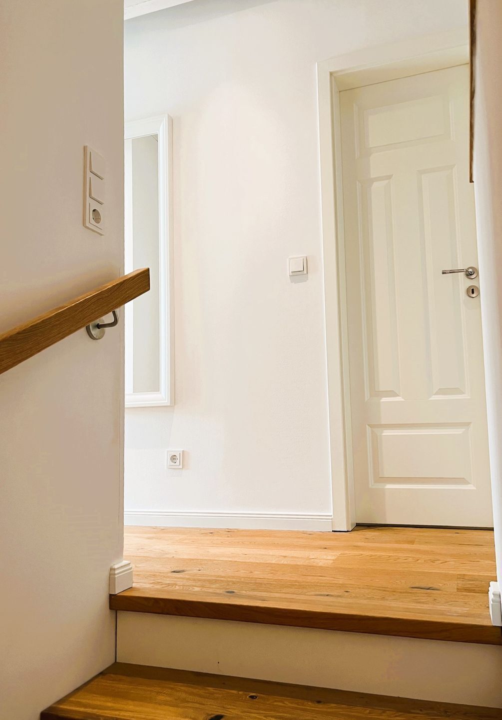 Un escalier avec des marches en bois menant à une porte blanche.