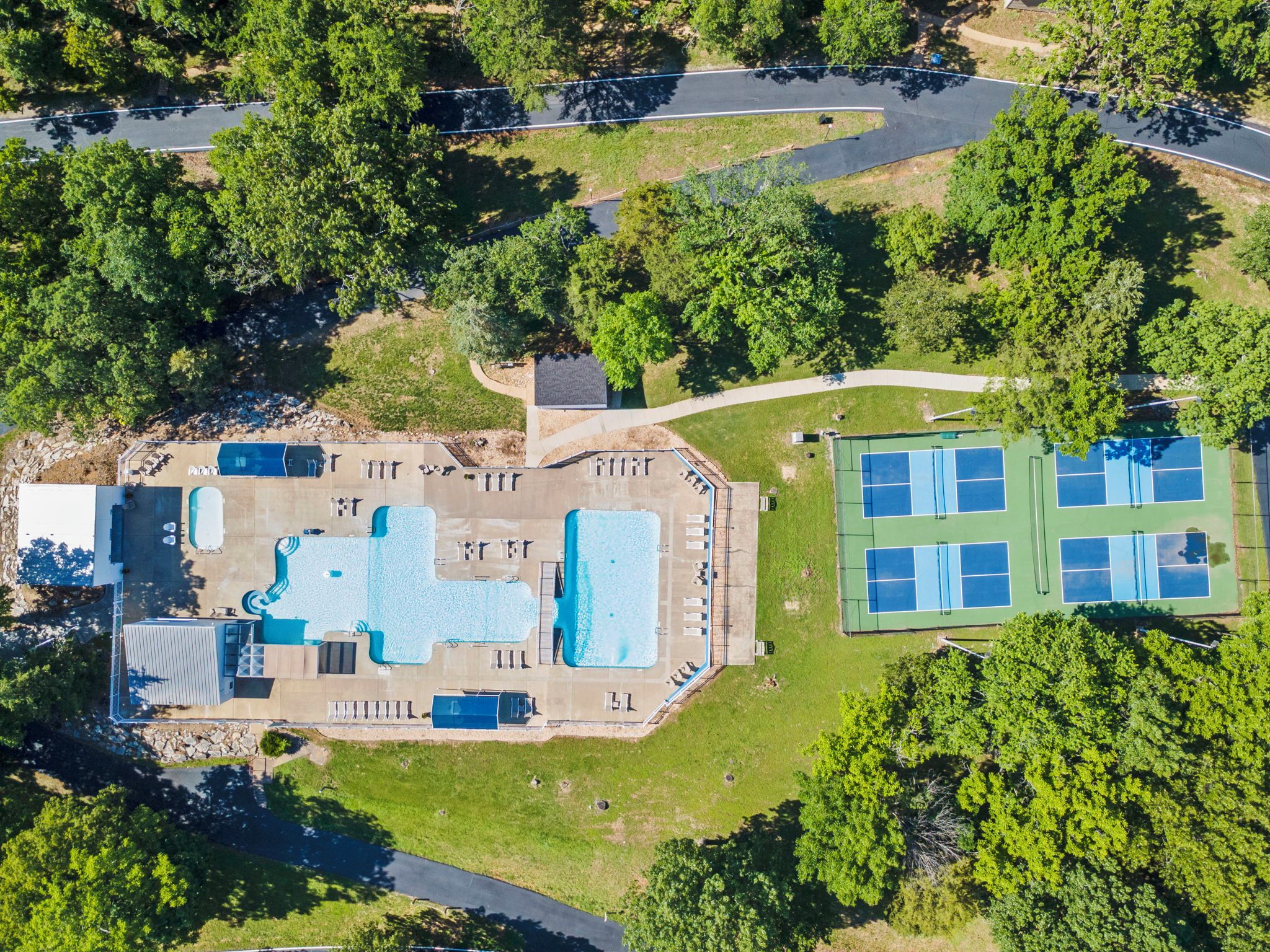 Ein Luftbild eines Resorts mit Schwimmbad, Tennisplätzen und einem Parkplatz.