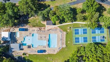 Ein Luftbild eines Resorts mit Schwimmbad, Tennisplätzen und einem Parkplatz.