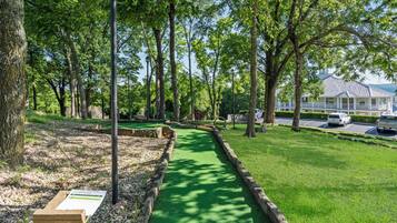 Een golfbaan met een groene pad, bomen en een gebouw op de achtergrond.