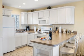 Una cocina moderna con armarios blancos, microondas integrado y una isla central con asientos.