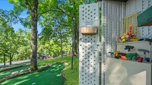 Een metalen constructie met een prikbord waarop kleurrijke gereedschappen, een houten doos en een lantaarnpaal staan.