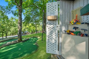 Une structure métallique dotée d’un panneau perforé où sont accrochés des outils de différentes couleurs, une boîte en bois et un lampadaire.